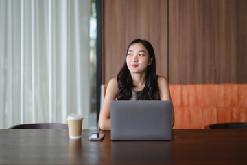Businesswoman working with laptop and enjoying coffee break in modern office