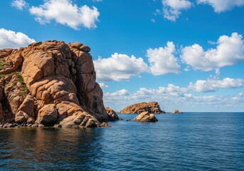 Rocky island formation in a tranquil blue sea under a bright sky with scattered clouds