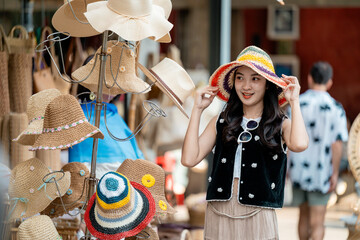 Young woman trying on a colorful straw hat in a traditional market
