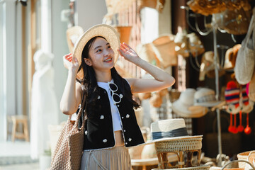 Young tourist adjusting her straw hat while visiting a traditional Thai market