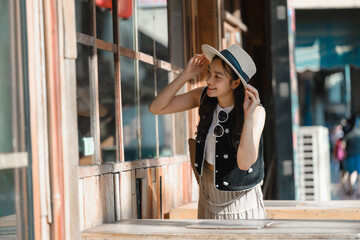 Young tourist adjusting her hat while looking at a shop window