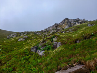 Rocky Green Hillside with Scenic Cliff View Under Overcast Sky