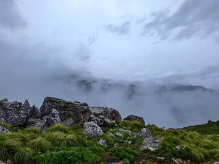 Misty Rocky Mountain Landscape with Grassy Hills and Dramatic Terrain