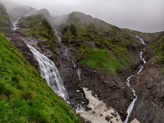 Misty Mountain Waterfall Cascading Over Mossy Rocks with Scenic Valley View