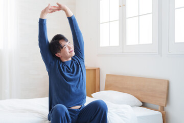 朝ベッドから起きてストレッチする男性