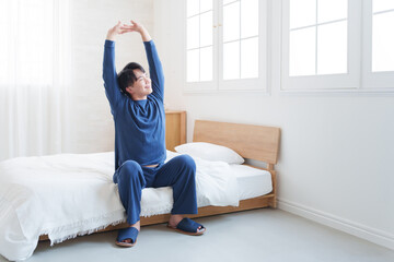 朝ベッドから起きてストレッチする男性