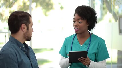 Healthcare professional consulting with a patient using a digital tablet outdoors on a sunny day