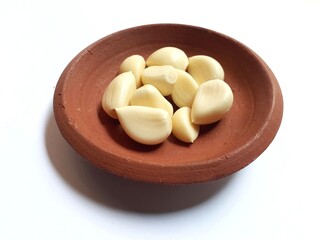 peeled garlic in a clay bowl isolated on white background