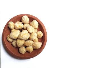 Fototapeta premium top view of candlenuts in a clay bowl, isolated on a white background