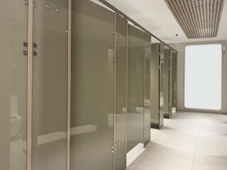 Public Restroom Stalls with Frosted Glass Doors and empty notice board mockup. Row of doors in...