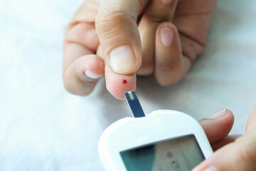 Woman's hands checking diabetes and hyperglycemia with digital blood sugar meter. Healthcare and...