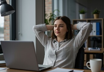 30-year-old caucasian woman relaxing with hands behind head in front of laptop in office - work-life balance concept