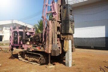 Fototapeta premium Pile driver machine is driving square prestressed concrete pile into the ground at a construction site. 