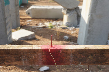 Nail is driven into wooden bars to be tied to fishing lines to serve as a line of sight during construction work.  