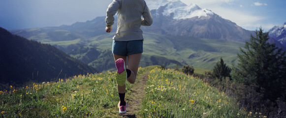 Trail runner running on the high altitude grassland mountain top trail