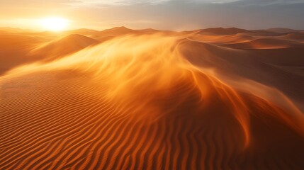Golden light bathes the sand dunes as a strong wind whips across the desert landscape creating swirling patterns and textures in the warm evening air around the ridges.