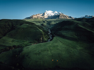 Aerial view of beautiful high altitude snow capped mountains and forest grassland landscape in China