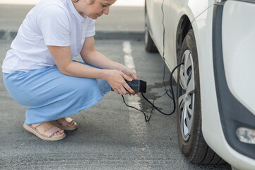 A woman pumps up a tire on a car. 