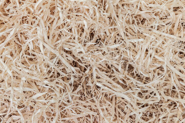 Close-up view of shredded material, possibly paper or cardboard, with no clear direction or pattern Predominantly off-white or light brown in color No text present Sharp focus for detailed observa