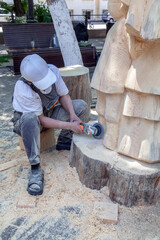 Man is carving a wooden sculpture with a power tool