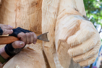 Man is carving a wooden statue with a chisel