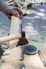 Man is using an axe to cut a piece of wood