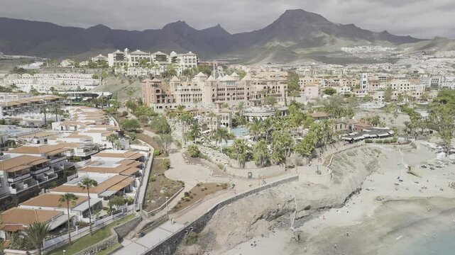 Drone, over the water, flies to the right facing Playa del Duque in Costa Adeje, Tenerife, Canary Islands, Spain