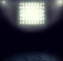 Flat design is showing dark stage with square floodlight grid and spotlights cutting scuffed floor
