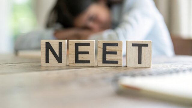 Blurred minimalist background with wooden blocks spelling NEET in simple composition
