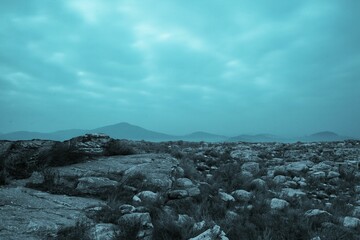 Barren rocky plateau is stretching under overcast sky in flat design, with scattered grass clusters