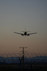 A commercial airplane approaches a runway during dusk