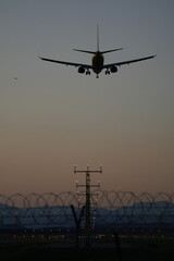A commercial airplane approaches a runway during dusk