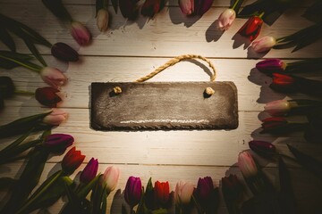 Flat design is showing blank chalkboard sign with rope handle on white plank with tulip wreath