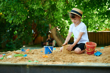 A six-year-old girl plays in a sandbox
