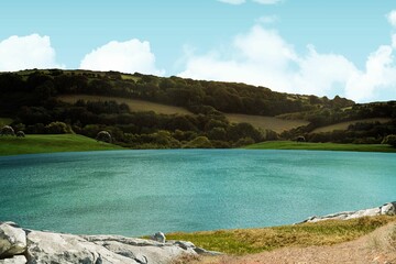 Calm turquoise lake is mirroring clouds, edging grassy bank, winding path, rolling hills