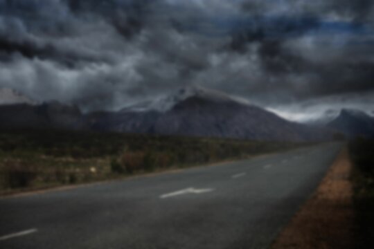 Fototapeta Road by mountain against stormy clouds