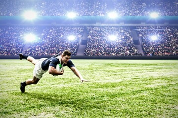 Rugby player jumping with the ball in sports stadium
