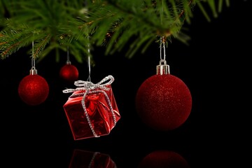 Cluster of red ornaments is hanging from green pine branch in 3D render with black background © vectorfusionart