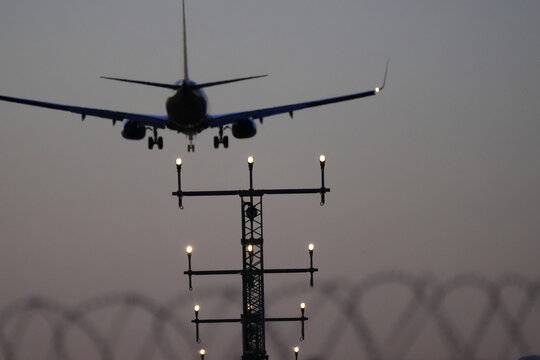 A commercial airplane approaches a runway during dusk