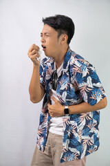 Young asian man wearing blue summer shirt is suffering sore throat and coughing holding his neck...