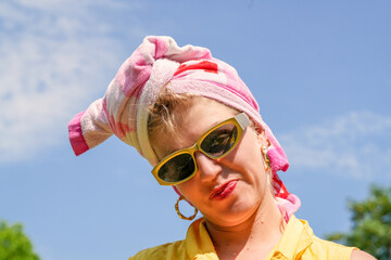 Junge Frau mit Badetuch um den Kopf und goldener Sonnenbrille hat Spass und zieht Grimassen