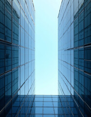 Obraz premium Symmetrical Modern Glass Facade Buildings Framing Bright Blue Sky