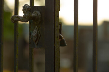 This image features a closeup view of a sturdy metal gate that has a secure lock attached to it,...