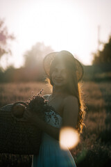 Woman holding baskets of flowers at sunset in a lavender field, enjoying nature's beauty