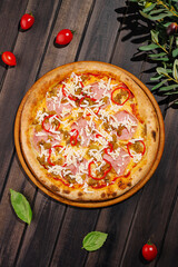 Freshly baked pizza with toppings on a wooden table surrounded by vegetables