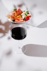 Elegant red wine glass topped with charcuterie, fruits, cheese, and nuts — a refined pairing perfect for gourmet gatherings or upscale wine tastings.