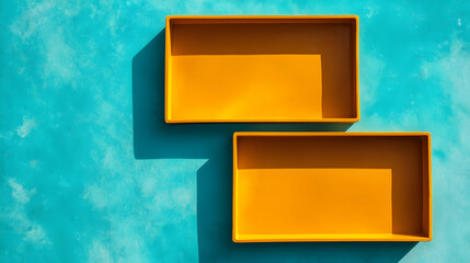 Minimalist top view of two yellow rectangular trays casting long shadows on bright turquoise background. Modern design with bold contrast and geometric balance.