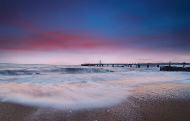Calm Seashore with Ocean Waves and Coastal Bridge at Sunset