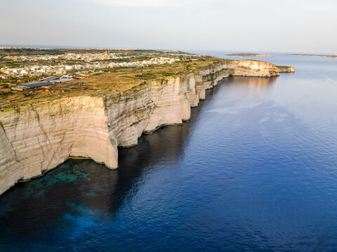 Aerial view of dramatic white cliffs plunging into the turquoise sea under a soft sky, creating a stunning coastal contrast, Munxar, Munxar, Malta.
