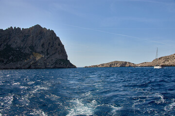Fototapeta premium Boat trip through the Calanques of Marseille with blue waters and rock formations under a clear Mediterranean sky
